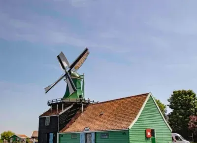 a green house with a windmill in the water